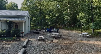 Level gravel area beside the event building with picnic tables and seating, suitable for crew support