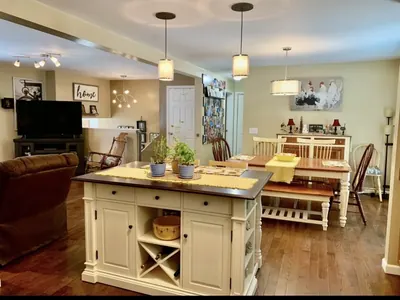 Open-plan kitchen and dining area with an island, pendant lighting and a long table