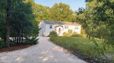 Gravel drive approaching the two-storey residence through mature trees