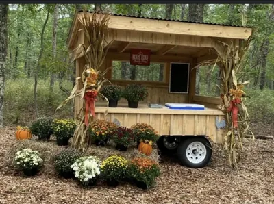 Timber farm stand dressed with autumn flowers, pumpkins and corn stalks