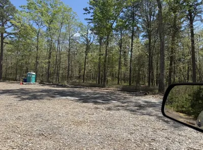 Open gravel staging and parking area surrounded by tall pines